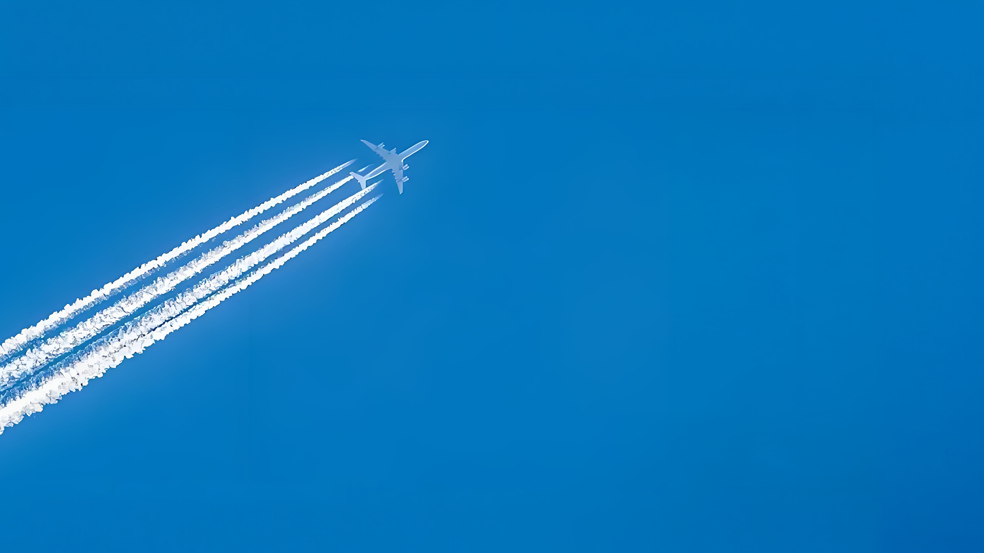 Airplane flying through clear blue sky with contrails